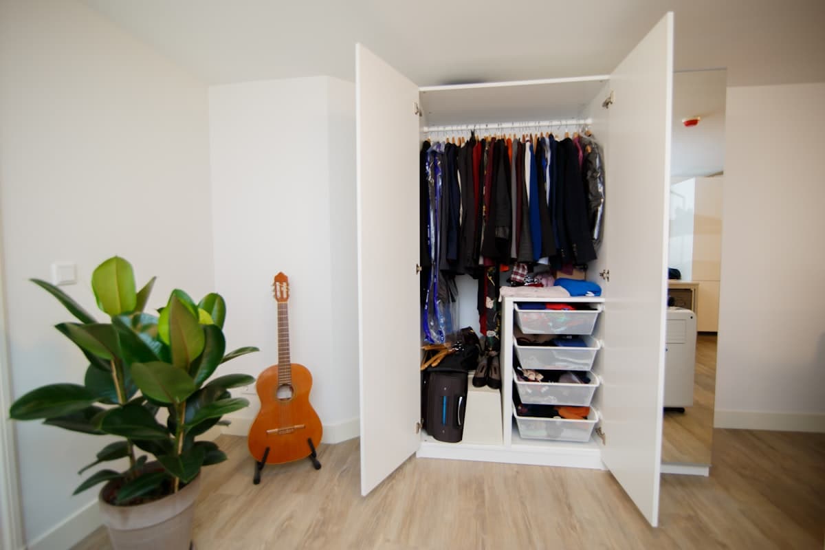 Foto de referencia: clóset a medida con puertas abiertas, ropa colgada y organizadores