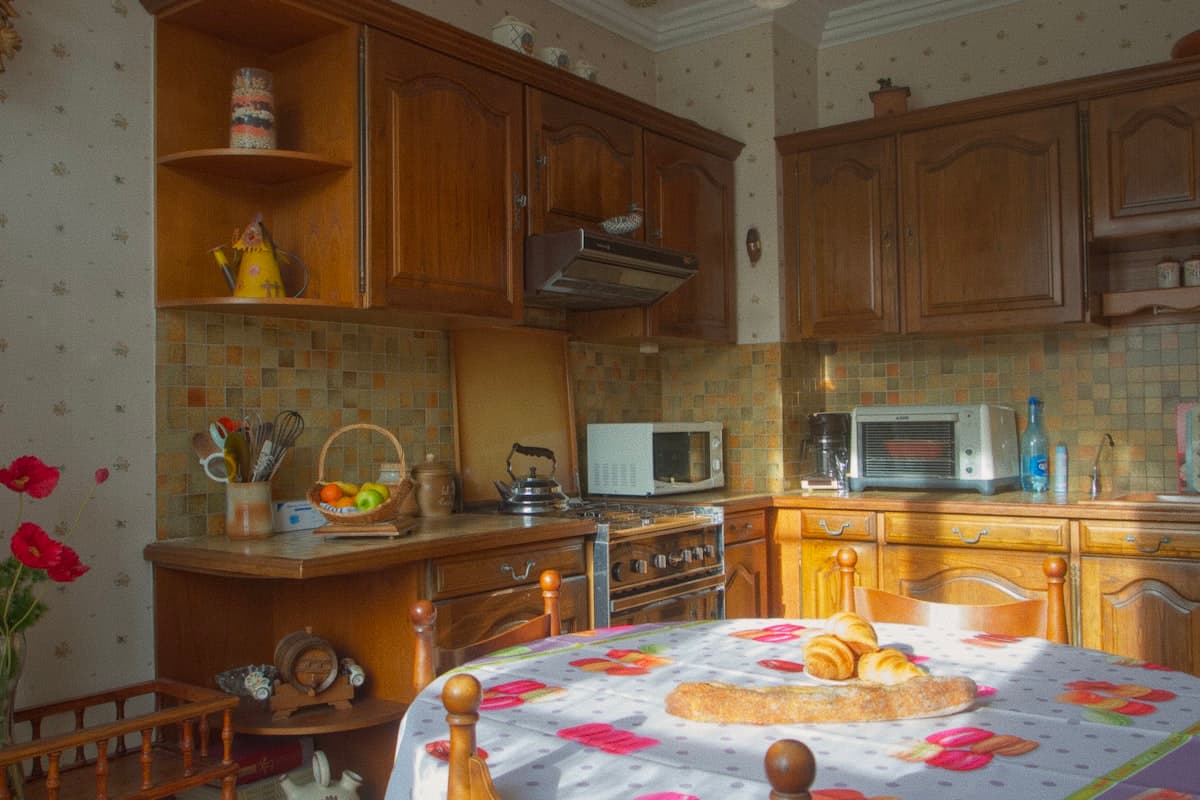 Foto de referencia: cocina antigua con muebles de madera oscura y mosaico años noventa