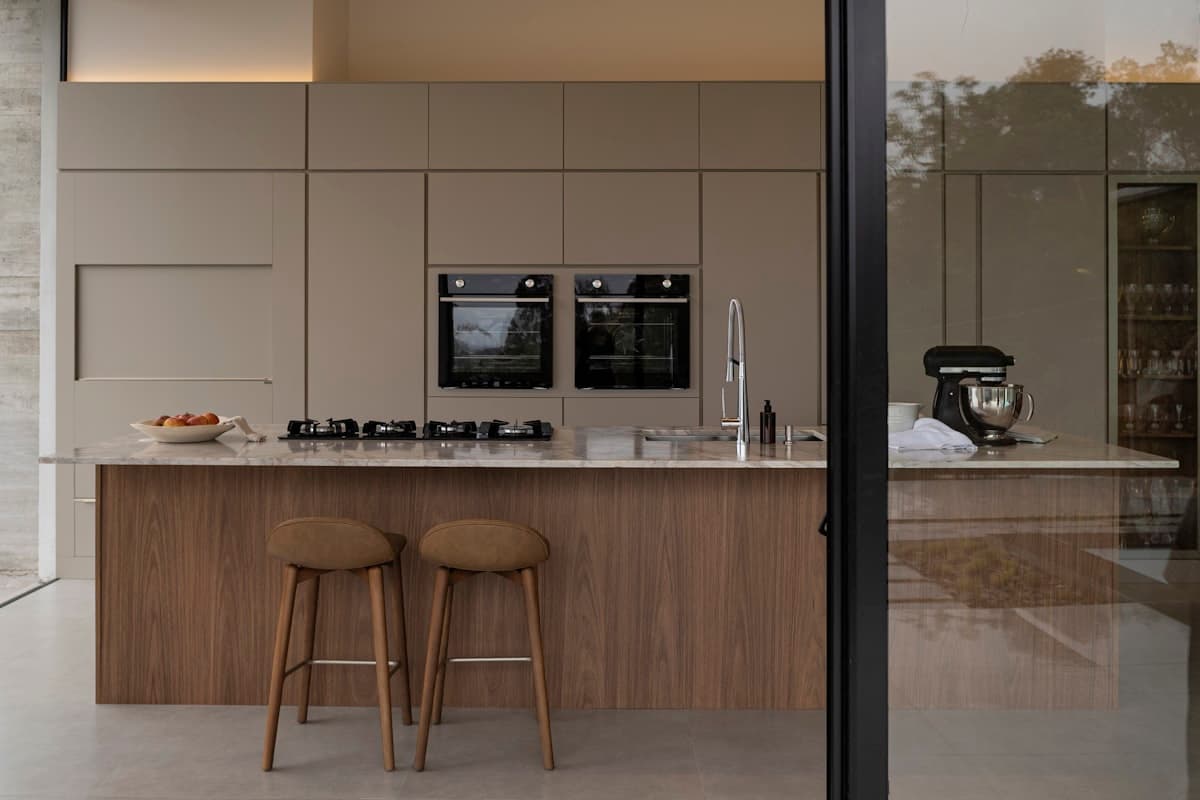 Foto de referencia: cocina moderna abierta con isla central, banquetas y acabados claros